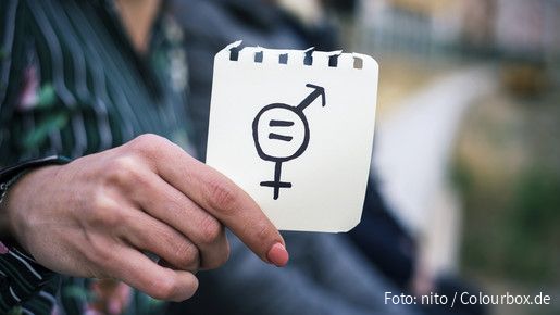 Frau hält Zettel mit Gleichheitssymbol (Symbolbild)