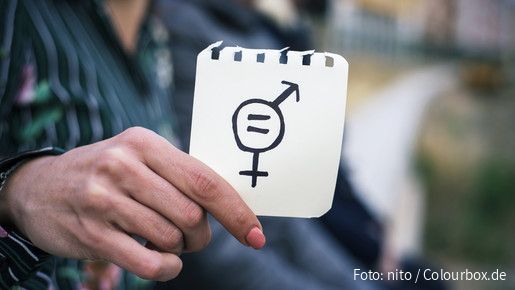 Frau hält Zettel mit Gleichheitssymbol (Symbolbild)